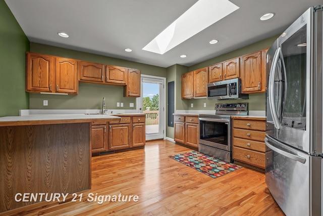2364 Milford Dr, Saginaw, MI 48603 - kitchen featuring appliances with stainless steel finishes, a skylight, light wood-style floors, light countertops, and recessed lighting