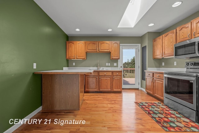 2364 Milford Dr, Saginaw, MI 48603 - kitchen with stainless steel appliances, a skylight, light countertops, light wood-style floors, and recessed lighting