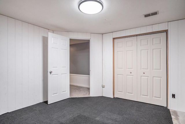 2104 Waterbury Dr SE, Kentwood, MI 49508 - unfurnished bedroom with carpet, wooden walls, a closet, and a decorative wall
