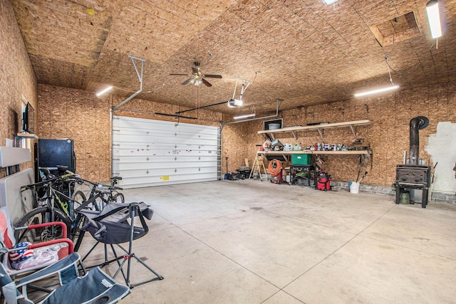 12467 S Running Deer Ln, Grant, MI 49327 - garage featuring a garage door opener, a ceiling fan, a wood stove, and a workshop area