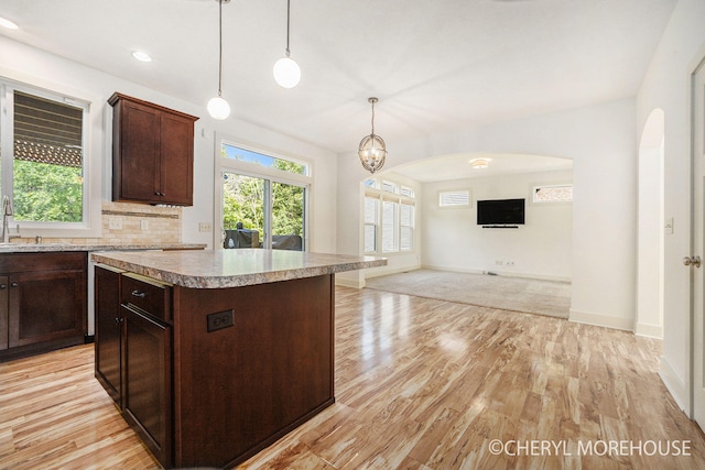 7511 Emerald Woods SE, Byron Center, MI 49315 - kitchen with arched walkways, light wood finished floors, light countertops, a kitchen island, and dark brown cabinetry
