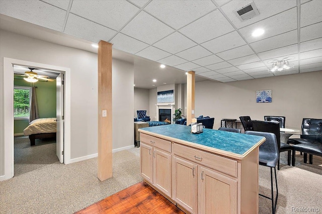 6280 Branford Dr, West Bloomfield, MI 48322 - kitchen featuring light brown cabinetry, a lit fireplace, light carpet, a breakfast bar area, and a paneled ceiling