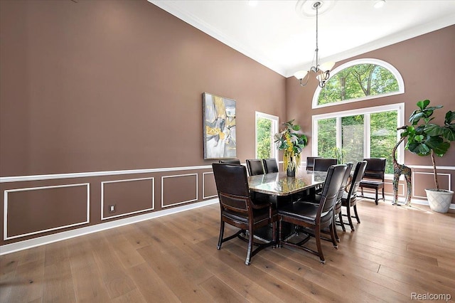 6280 Branford Dr, West Bloomfield, MI 48322 - dining area with a chandelier, wood-type flooring, crown molding, a decorative wall, and high vaulted ceiling
