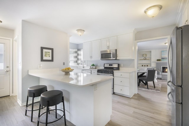 1915 Orville St SE, Grand Rapids, MI 49506 - kitchen with appliances with stainless steel finishes, a kitchen breakfast bar, white cabinetry, light wood-style floors, and light countertops