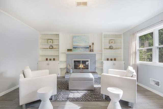 1915 Orville St SE, Grand Rapids, MI 49506 - living area featuring wood finished floors, built in shelves, crown molding, and a brick fireplace