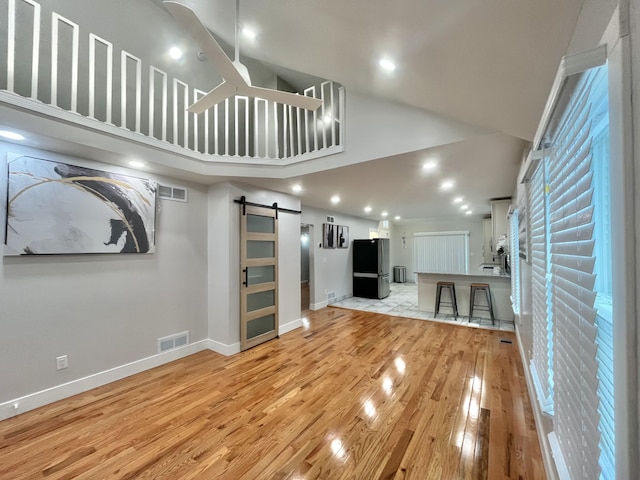 336 E Prospect St, Jackson, MI 49203 - unfurnished living room with a barn door, light wood-style floors, recessed lighting, and high vaulted ceiling