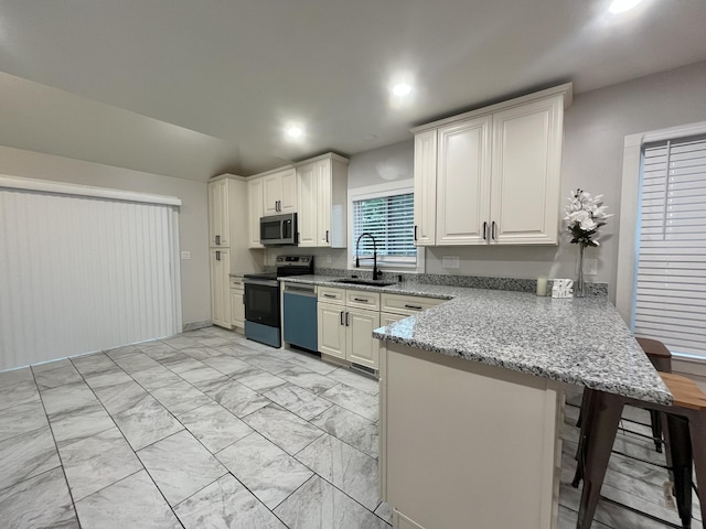 336 E Prospect St, Jackson, MI 49203 - kitchen featuring stainless steel appliances, a peninsula, a kitchen bar, light marble finish flooring, and light stone countertops