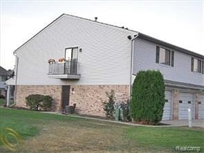 50102 S Benny Ct, New Baltimore, MI 48047 - view of side of home with a garage, a yard, a balcony, and stone siding