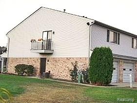 50102 S Benny Ct, New Baltimore, MI 48047 - view of home's exterior featuring a garage, a yard, a balcony, and stone siding