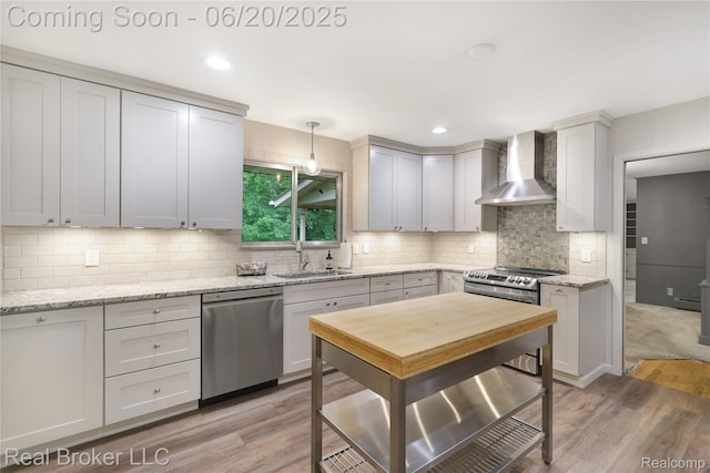 5492 N Sycamore Dr, Burton, MI 48509 - kitchen featuring appliances with stainless steel finishes, wall chimney range hood, light wood-type flooring, decorative backsplash, and recessed lighting