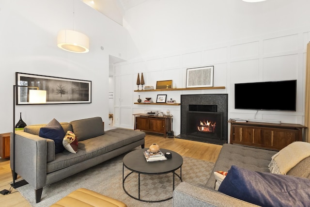 9435 Community Hall Rd, Union Pier, MI 49129 - living room featuring high vaulted ceiling, light wood finished floors, and a warm lit fireplace