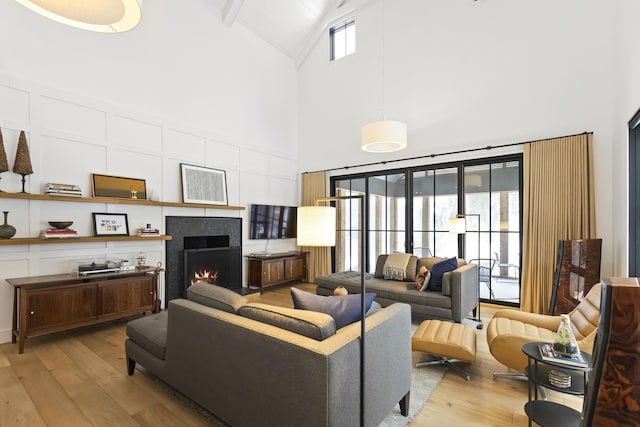 9435 Community Hall Rd, Union Pier, MI 49129 - living area featuring high vaulted ceiling, light wood-style floors, a warm lit fireplace, and beamed ceiling