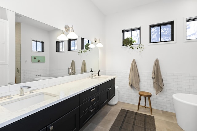 9435 Community Hall Rd, Union Pier, MI 49129 - bathroom with a freestanding bath, double vanity, tile walls, wainscoting, and a stall shower
