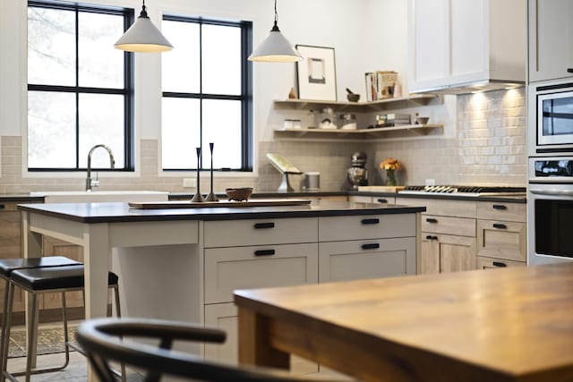 9435 Community Hall Rd, Union Pier, MI 49129 - kitchen featuring appliances with stainless steel finishes, dark countertops, tasteful backsplash, hanging light fixtures, and healthy amount of natural light