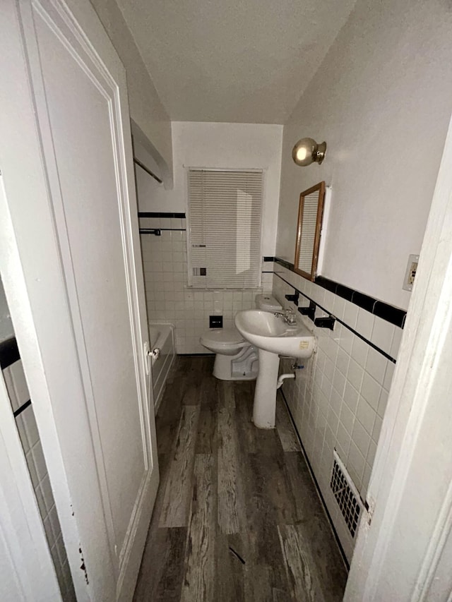 15345 Marlowe St, Detroit, MI 48227 - bathroom featuring tile walls, wood finished floors, wainscoting, and a tub