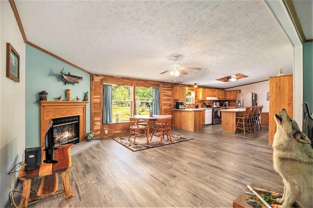 4890 W Birch Ln, Pentwater, MI 49449 - dining area with ornamental molding, light wood-style floors, a glass covered fireplace, ceiling fan, and a textured ceiling