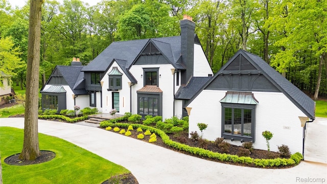 163 Manorwood Dr, Bloomfield Hills, MI 48304 - view of front facade featuring a chimney, a standing seam roof, a shingled roof, brick siding, and view of scattered trees