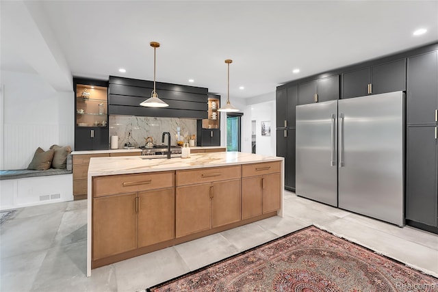 163 Manorwood Dr, Bloomfield Hills, MI 48304 - kitchen with high end fridge, a center island with sink, pendant lighting, tasteful backsplash, and light stone countertops