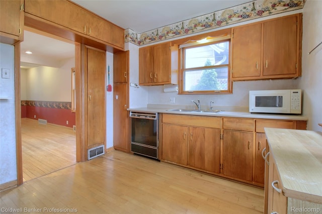 21732 Tenny St, Dearborn, MI 48124 - kitchen featuring black dishwasher, white microwave, light wood-style flooring, and light countertops