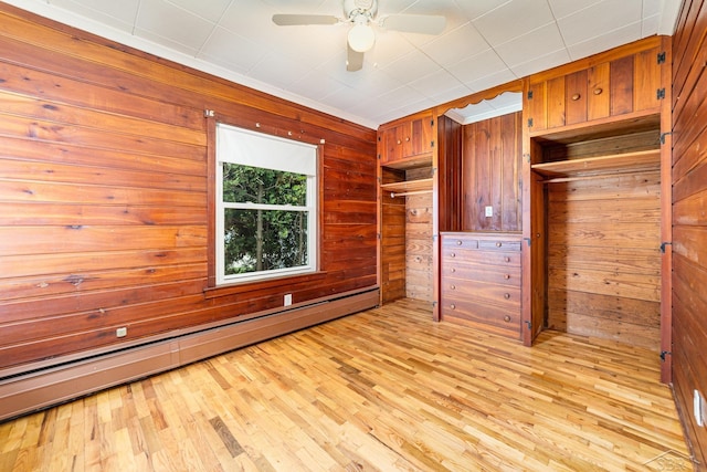395 S Center Rd, Saginaw, MI 48638 - unfurnished bedroom with wood walls, a baseboard heating unit, and light wood-style floors