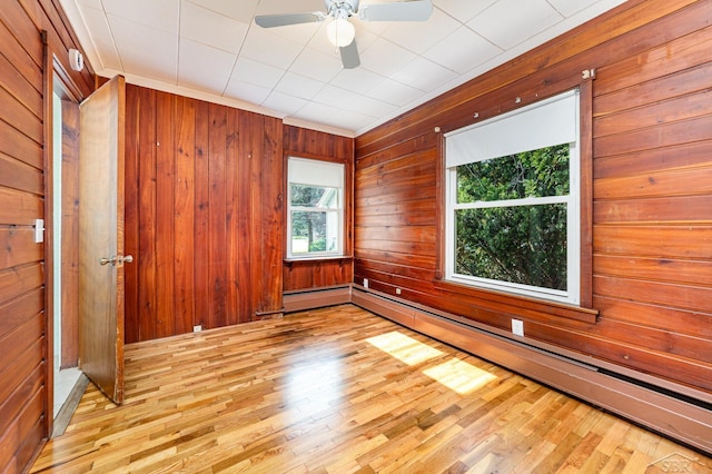 395 S Center Rd, Saginaw, MI 48638 - unfurnished room featuring a baseboard heating unit, ornamental molding, light wood-type flooring, wooden walls, and a ceiling fan