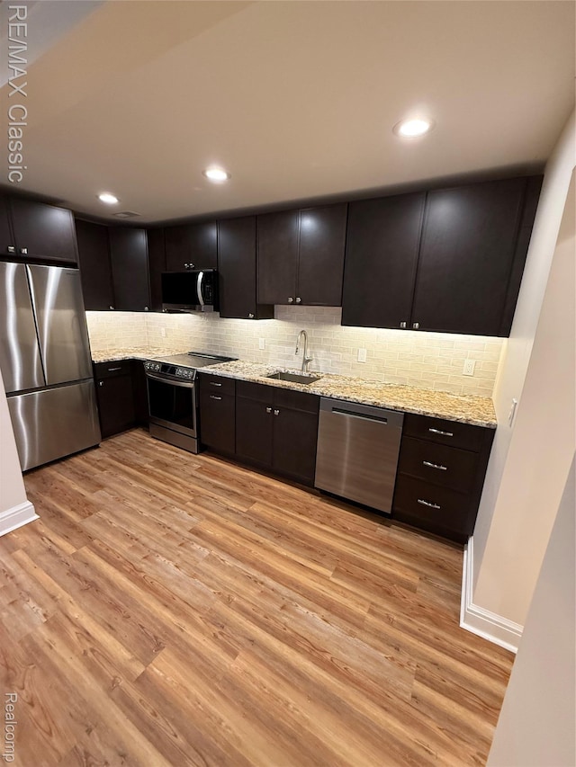 1420 Pettibone Lake Rd, Highland, MI 48356 - kitchen featuring appliances with stainless steel finishes, light wood-style floors, light stone counters, tasteful backsplash, and recessed lighting