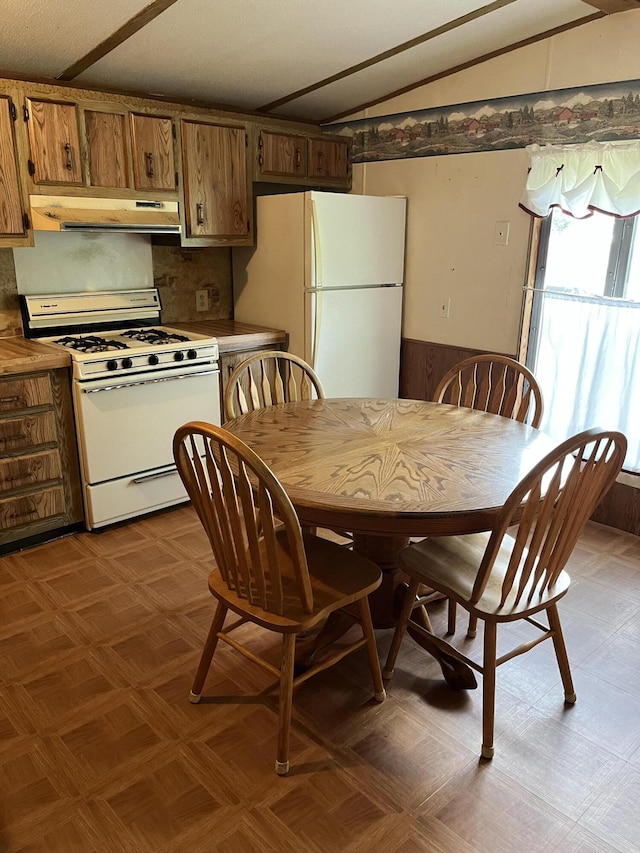 6121 N Pine Ave, White Cloud, MI 49349 - kitchen featuring white appliances, under cabinet range hood, lofted ceiling, brown cabinetry, and light floors