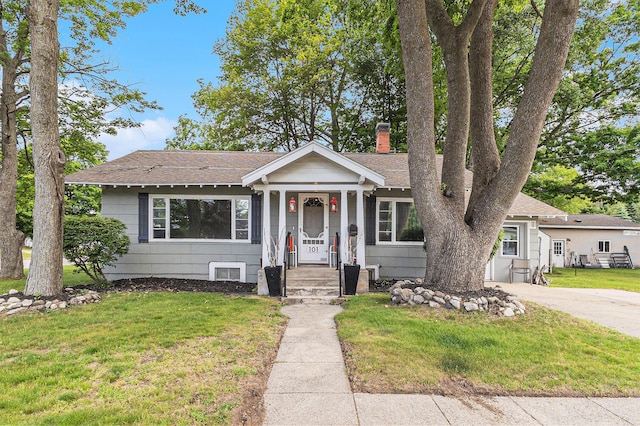 101 E Whittier St, Ludington, MI 49431 - view of front facade with a chimney, a shingled roof, and a front yard