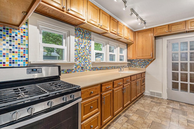 101 E Whittier St, Ludington, MI 49431 - kitchen with stainless steel range with gas cooktop, light countertops, decorative backsplash, and brown cabinets