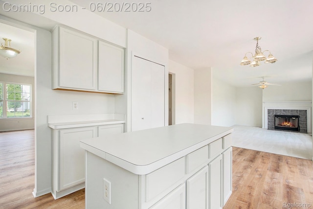3244 Buckhorn Ct, Ann Arbor, MI 48105 - kitchen featuring light wood finished floors, a chandelier, a kitchen island, a tile fireplace, and light countertops