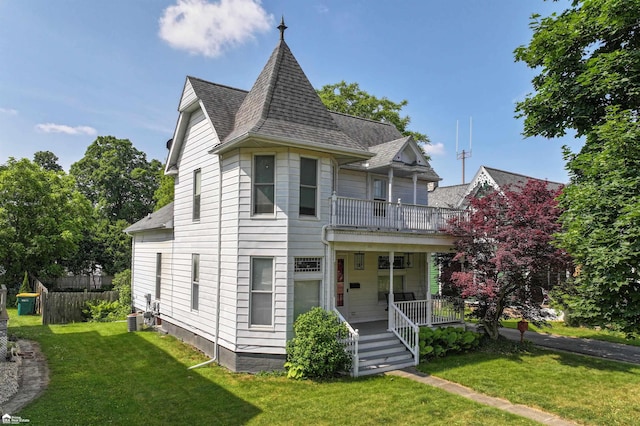 320 E Main St, Flushing, MI 48433 - victorian-style house featuring a balcony, covered porch, a front lawn, and a shingled roof