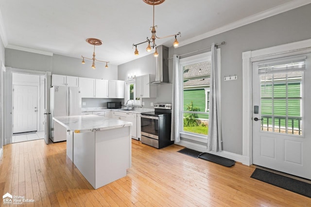 320 E Main St, Flushing, MI 48433 - kitchen with white appliances, wall chimney range hood, a center island, light wood-type flooring, and crown molding