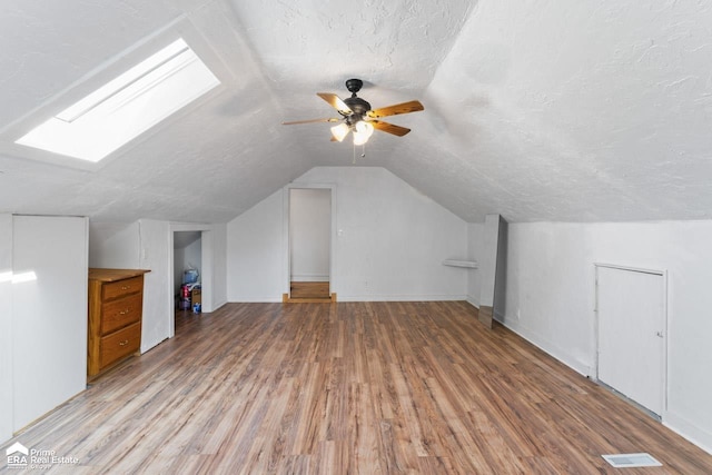 320 E Main St, Flushing, MI 48433 - additional living space with a skylight, light wood-style floors, vaulted ceiling, ceiling fan, and a textured ceiling