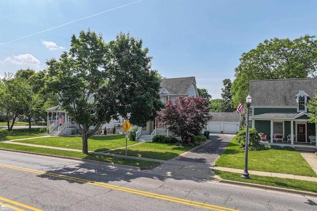 320 E Main St, Flushing, MI 48433 - view of front of house featuring covered porch, a front yard, a garage, an outbuilding, and a shingled roof