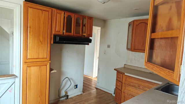 5157 Niagara St, Wayne, MI 48184 - kitchen featuring wood finished floors, decorative backsplash, brown cabinets, and glass insert cabinets
