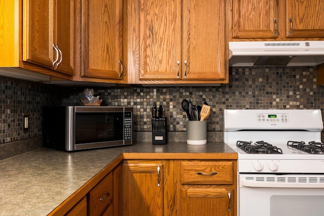 1724 N Ridge Rd, Mears, MI 49436 - kitchen with white range with gas cooktop, under cabinet range hood, stainless steel microwave, decorative backsplash, and dark countertops