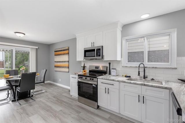 14671 Labelle St, Oak Park, MI 48237 - kitchen featuring stainless steel appliances, backsplash, white cabinets, light stone countertops, and light wood-style floors