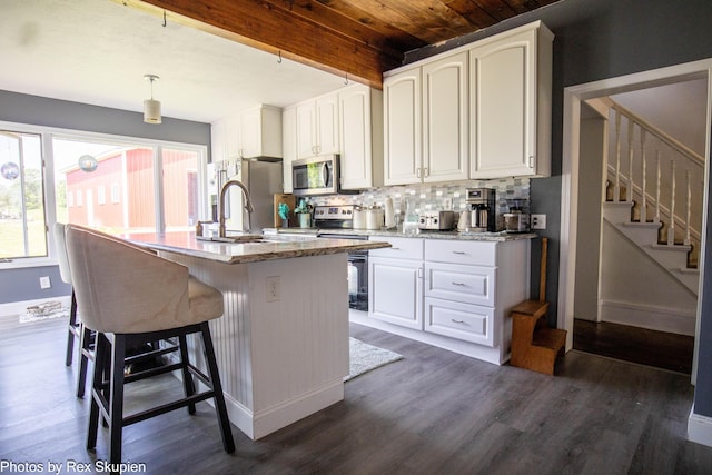 4295 S Gordon Ave, Fremont, MI 49412 - kitchen with stainless steel appliances, backsplash, dark wood-type flooring, an island with sink, and a wood ceiling with exposed beams