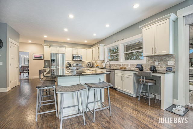 12828 Bayou Ct, Wayland, MI 49348 - kitchen featuring stainless steel appliances, a breakfast bar, decorative backsplash, recessed lighting, and dark wood-type flooring