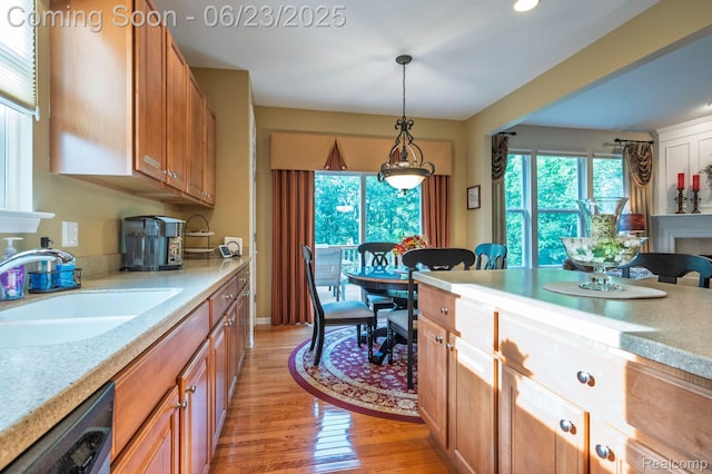 601 Acadia Ct, Howell, MI 48843 - kitchen with dishwashing machine, light countertops, light wood-style flooring, pendant lighting, and brown cabinetry