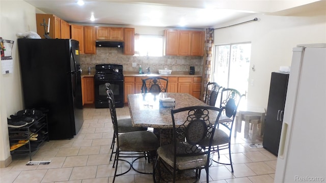 27038 Grobbel Dr, Warren, MI 48092 - kitchen with black appliances, under cabinet range hood, light tile patterned floors, backsplash, and light countertops