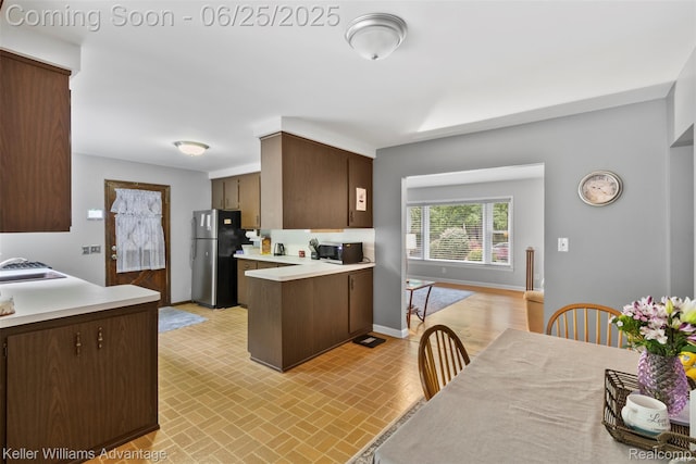 29866 Woodland Dr, Southfield, MI 48034 - kitchen featuring appliances with stainless steel finishes, light countertops, brick patterned flooring, a peninsula, and dark brown cabinets