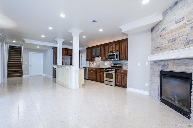 56343 Via Serbelloni, Macomb, MI 48042 - kitchen featuring stainless steel appliances, a fireplace, ornate columns, a kitchen breakfast bar, and crown molding