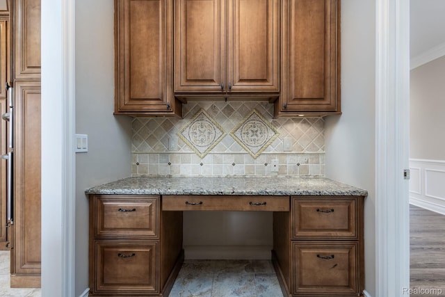56343 Via Serbelloni, Macomb, MI 48042 - kitchen with built in desk, light stone counters, backsplash, a wainscoted wall, and ornamental molding