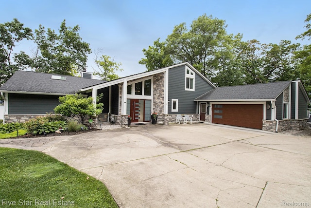 7025 Dandison Blvd, West Bloomfield, MI 48324 - mid-century inspired home featuring stone siding, an attached garage, concrete driveway, and a chimney
