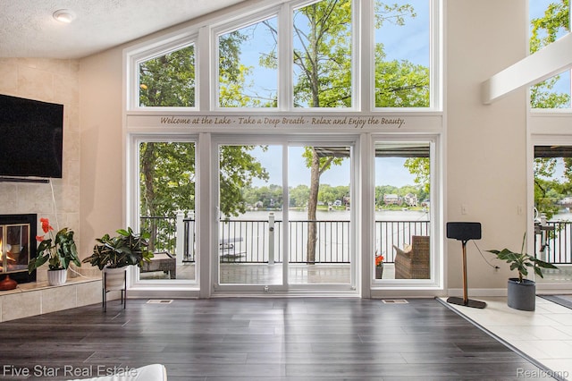 7025 Dandison Blvd, West Bloomfield, MI 48324 - entryway with a tile fireplace, a water view, wood finished floors, a towering ceiling, and a textured ceiling