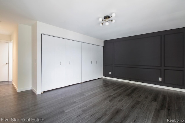 7025 Dandison Blvd, West Bloomfield, MI 48324 - unfurnished bedroom featuring a closet, dark wood-style flooring, and a decorative wall