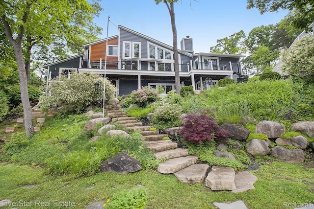 7025 Dandison Blvd, West Bloomfield, MI 48324 - back of property with a chimney, stairs, and a deck