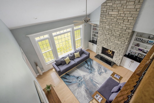 6577 Heron Ct, Ann Arbor, MI 48103 - living room featuring wood finished floors, a large fireplace, ceiling fan, built in features, and high vaulted ceiling