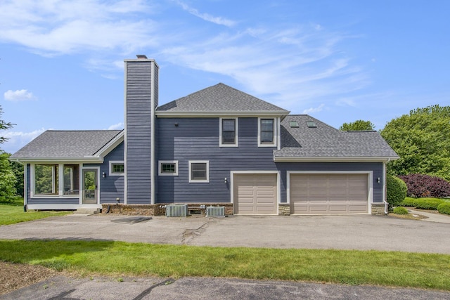 6577 Heron Ct, Ann Arbor, MI 48103 - rear view of house with a chimney, asphalt driveway, an attached garage, and roof with shingles